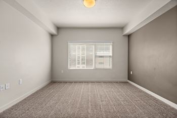 A room with a carpeted floor and a window with blinds.